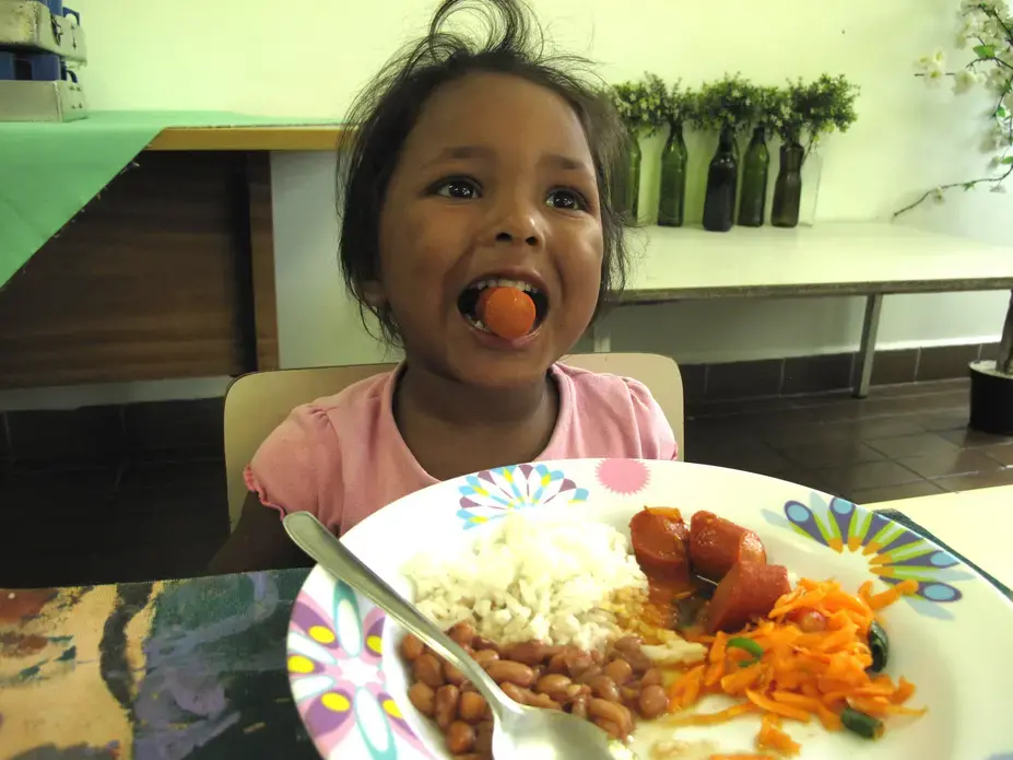 A child in Sao Paulo eats lunch provided at her day care. This meal is part of Brazil's National School Feeding Program (PNAE), which feeds 43 million children. Image by Rhitu Chatterjee. Brazil, 2015. Media file: brazil_039.jpg