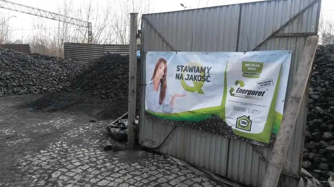 "Quality is our priority," says the banner at Grzegorz Rumin's coal lot. "100 percent Polish coal." However, experts say coal burned in Polish homes is often low quality and highly polluting. Image by Beth Gardiner. Poland, 2015. Media file: poster_at_coal_lot.jpg