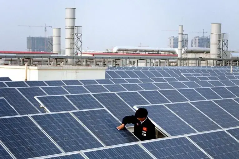 A worker cleans a solar panel on top of a factory building in Baoding City. China is installing a soccer field's worth of solar panels every hour. Image by Sean Gallagher. China, 2017.