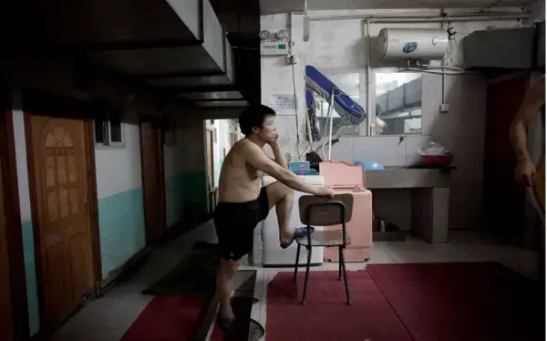 A resident waits to use the communal bathroom and washing area of a basement hostel on the western outskirts of Beijing. Image by Sim Chi Yin. China, August 20, 2011. Media file: chiyin.png