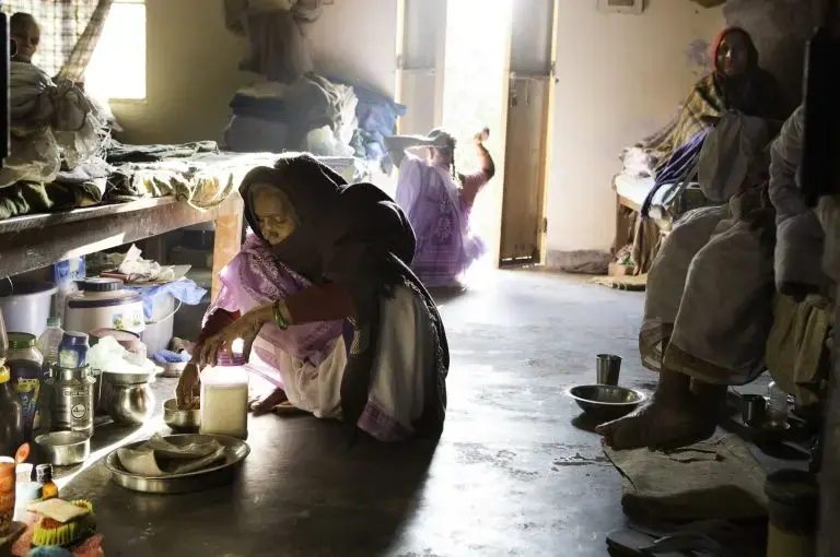 Elderly widows cook next to their beds at Tarash Mandir, a short-stay home for young women and permanent facility for elderly widows in Vrindavan. Image by Amy Toensing. India, 2016.