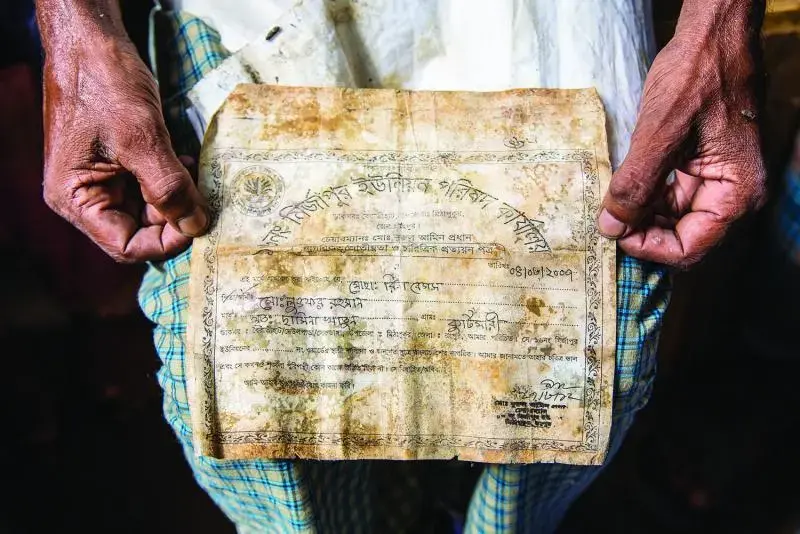 Lutfer Rahman holds the document that his daughter found next to the body of his wife, Rina Rahman, confirming her death in the collapse. Image by Jason Motlagh. Bangladesh, 2014. Media file: 800x534xmotlagh.jpg