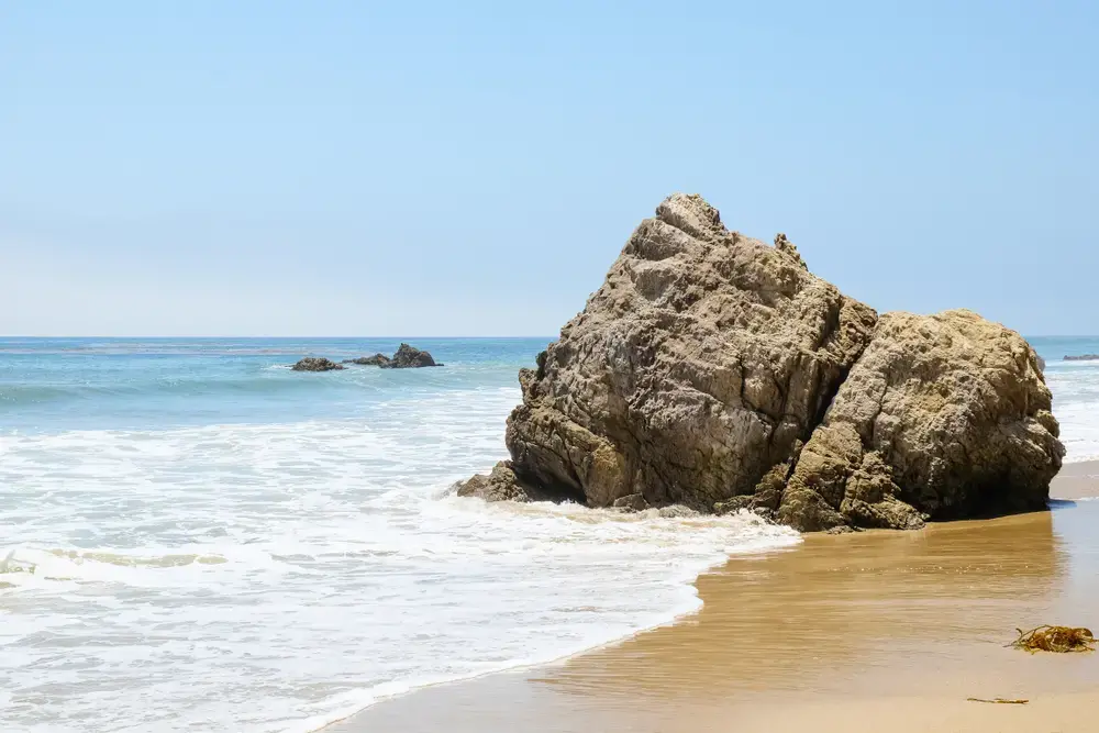 Rocks in the ocean on a sunny day at Broad Beach in Malibu, California. Image by Shutterstock. United States, undated.