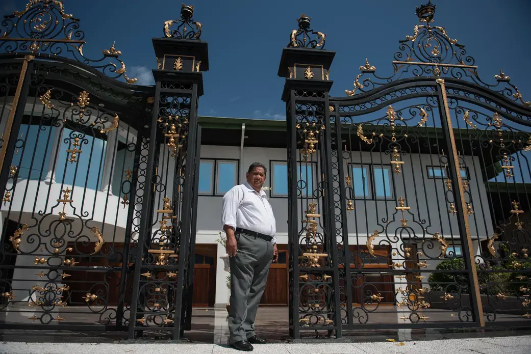 Rudi Dilip Sardjoe at the gates of his residential and office compound in Paramaribo, Suriname. Image by Stephanie Strasburg. Suriname, 2017.