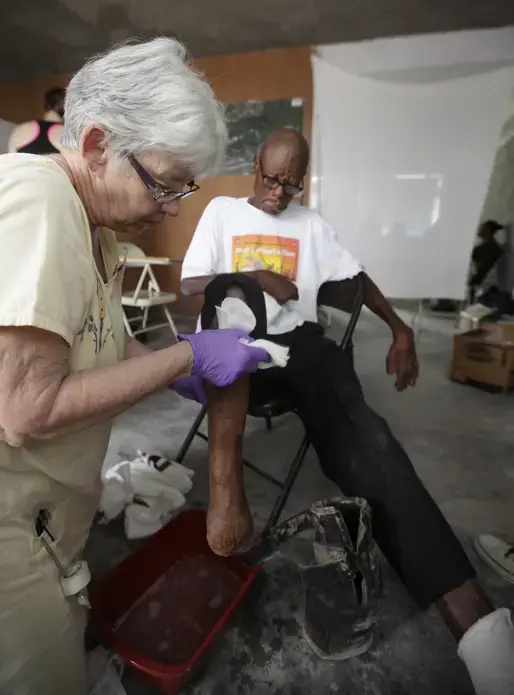 Nurse Jan Palmer of Minnesota washes the foot of leprosy patient Jean Stefen Youyoute, 67. Image by Mary Chind. Haiti, 2013. Media file: dmrdc5-69kvspu5krkmd4hdog1_original.jpg