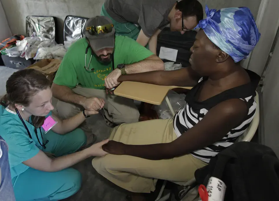University of Iowa nurse Casey Panko, left, and Dr. Chris Buresh pray with patient Cedamise Belvert after telling her she has advanced lymphoma and probably won't live much longer. Image by Mary Chind. Haiti, 2013. Media file: dmrdc5-69qsfsdy8omapp3m92p_original.jpg