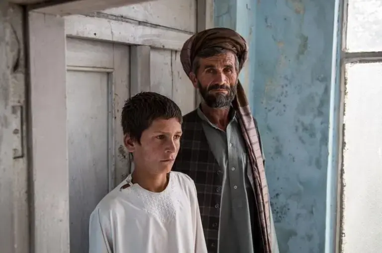 Nawroz and his son Zewarshah at their home in Charkh, Aghanistan, in 2015. Nawroz had sent his sons out to collect grain on the morning of August 3 only to have Zewarshah witness the death of his younger brother, Ayman, whose nickname was Sufi. Image by Jason Motlagh. Afghanistan, 2015.