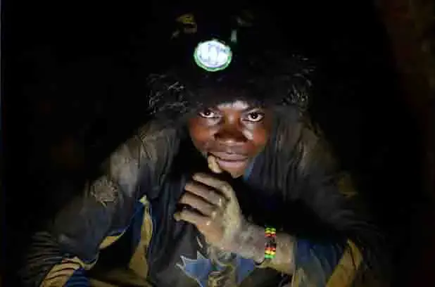 A young miner shines his headlamp underground in the mine where he scours for tin ore. Image by Fiona Lloyd-Davies. DRC, 2013. Media file: minefld.jpg