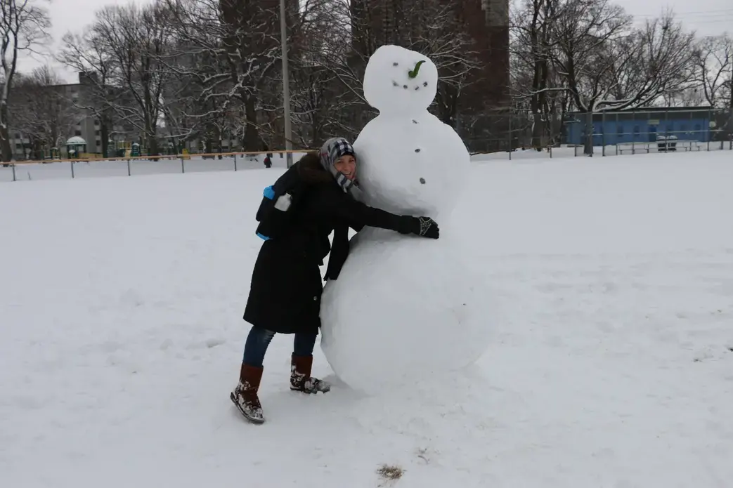 Raghda Altellawi hugs a snowman she discovers on her first day of school in Canada. Image by Robin Shulman. Canada, 2016. Raghda hugs a snowman