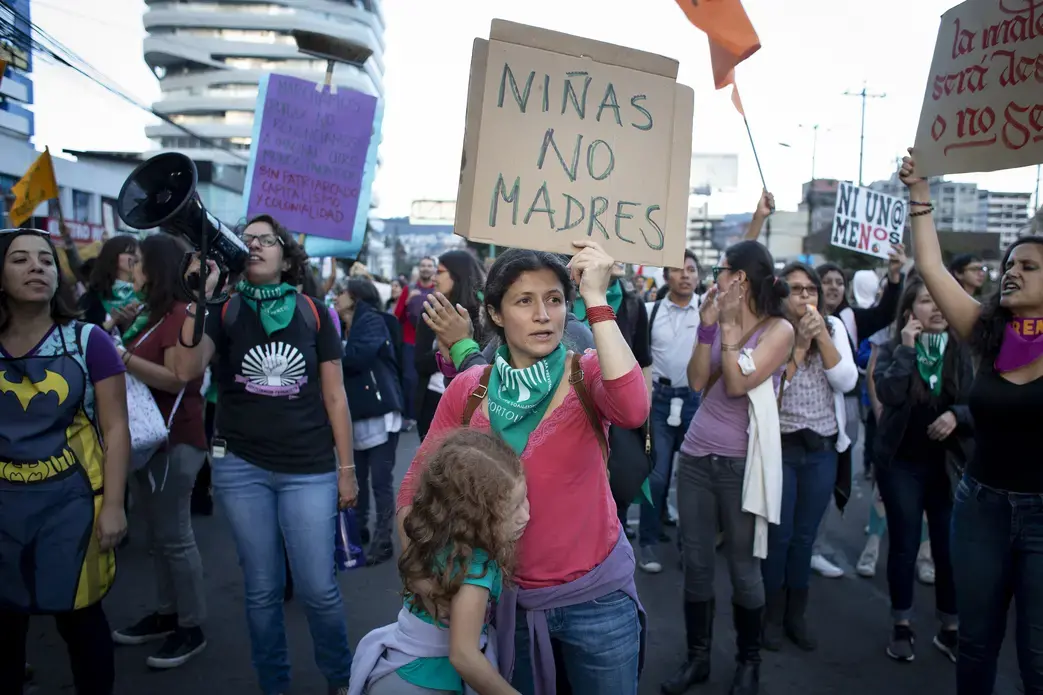A woman hugs her daughter while holding a sign that says “Girls Not Mothers” in Quito, Ecuador. She marched with hundreds of women on March 8 for women's rights in Ecuador and around the world. Image by Dominique Riofrío. Ecuador, 2019.