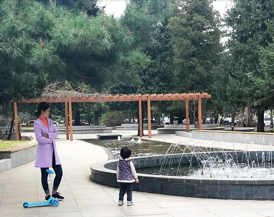 A young woman stands with her daughter in the park in front of Minzu University in Beijing. Image by Argentina Maria-Vanderhorst. China, 2018. A young woman stands with her daughter in the park in front of Minzu University in Beijing. Image by Argentina Maria-Vanderhorst. China, 2018.