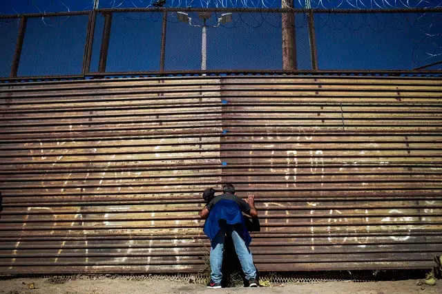 A Honduran migrant observes the displacement of the US military on the other side of the border wall. Image by Simone Dalmasso. Tijuana, 2018.
