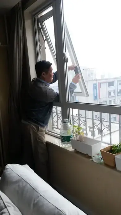 Zou Yi takes a photo of Beijing's air from the same window every day. He shares the images on social media, and compiles them into blue-and-grey checkerboard grids, turning pollution into art. Image by Beth Gardiner. China, 2017.