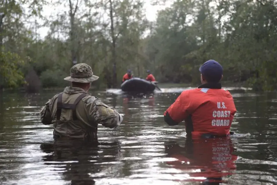Members of Coast Guard Maritime Safety and Security Team Miami and Coast Guard Tactical Law Enforcement Team South wait to be picked up by their rescue team after completing Hurricane Florence search and rescue operations in Brunswick County Sept. 16, 2018. Image by Petty Officer 3rd Class Trevor Lilburn. United States, 2018. Members of Coast Guard Maritime Safety and Security Team Miami and Coast Guard Tactical Law Enforcement Team South wait to be picked up by their rescue team after completing Hurricane Florence search and rescue operations in Brunswick County Sept. 16, 2018. Image by Petty Officer 3rd Class Trevor Lilburn. United States, 2018.