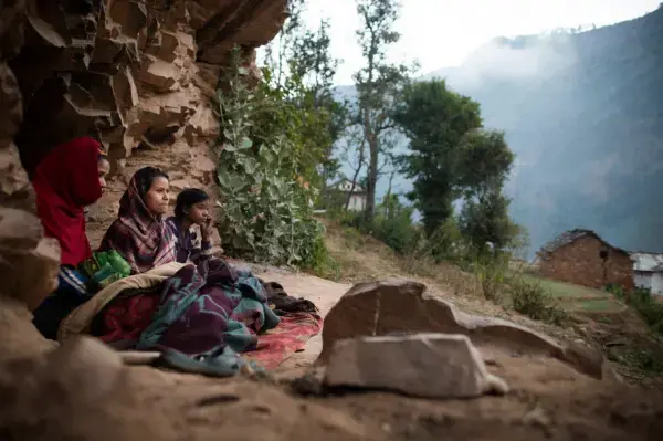 Young women observing chaupadi wake up under a rock outcropping in Kalekanda village, Achham, Nepal. Image by Allison Shelley. Nepal, 2012. Media file: allison.jpg
