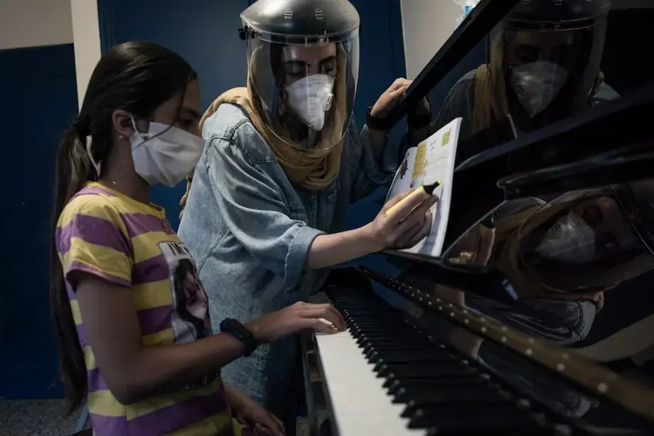 Double protection: 31-year-old Mojdeh teaches children to play the piano in Gorgan. But in the past two months, all of their courses have been canceled. Practicing with the kids on the internet didn't work. Now she gives a few private lessons, only three a day, and earns around 63 euros a month. It is not enough to pay for living expenses and debts. Finding special protective masks is difficult. In addition, according to Mojdeh, spraying disinfectant permanently damages the piano. Iranian singers, in turn, give online traditional-style singing lessons for middle and upper-class women, some of whom also pay for it. Image by Kianoush Saadati / NVP Images. Iran, 2020. Double protection: 31-year-old Mojdeh teaches children to play the piano in Gorgan. But in the past two months, all of their courses have been canceled. Practicing with the kids on the internet didn't work. Now she gives a few private lessons, only three a day, and earns around 63 euros a month. It is not enough to pay for living expenses and debts. Finding special protective masks is difficult. In addition, according to Mojdeh, spraying disinfectant permanently damages the piano. Iranian singers, in turn,…