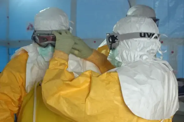 A Médecins Sans Frontières/Doctors Without Borders (MSF) staff member ties the face mask of Dr. Jordan Tappero, CDC, before Dr. Tappero enters an Ebola treatment unit. Image by CDC Global/Flickr, CC BY 2.0. Media file: msfebola.png