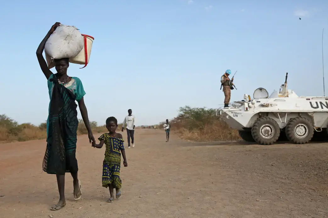 Internally displaced South Sudanese walk past a U.N. peacekeeper in Bentiu. Image by Cassandra Vinograd. South Sudan, 2016.