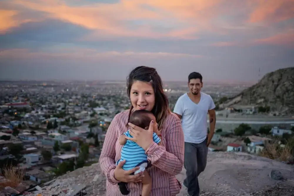 Denise Fuentes and Ulises Escobedo, posing on an overlook with baby Eros, both were touched by the drug war that raged in the neighborhood below. Now they’re searching for a home there. Image by Dominic Bracco II. Mexico, 2015.