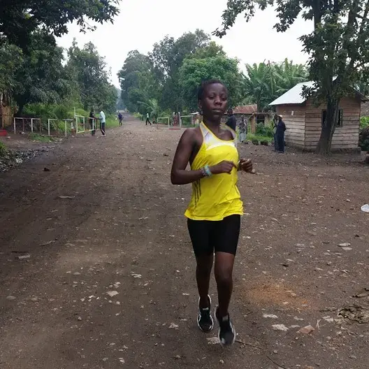 Beatrice Kamuchanga runs down the main road in Kirotshe. Each morning she trains in the mountains surrounding Lake Kivu as she prepares to run the 5000 meter race in the 2016 Olympic games. Image by Makorobondo Dee Salukombo. Democratic Republic of Congo, 2015. Beatrice Kamuchanga runs down the main road in Kirotshe, Democratic Republic of Congo.