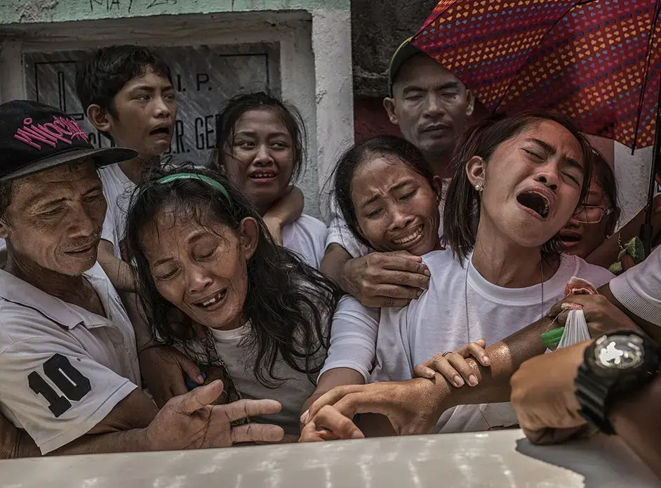 Pedro Abletes, on the far left, comforts his wife, as they say their final good-byes to their son, Junmar. Image by James Whitlow Delano. Philippines, 2017. Pedro Abletes, on the far left, comforts his wife, as they say their final good-byes to their son, Junmar. Image by James Whitlow Delano. Philippines, 2017.