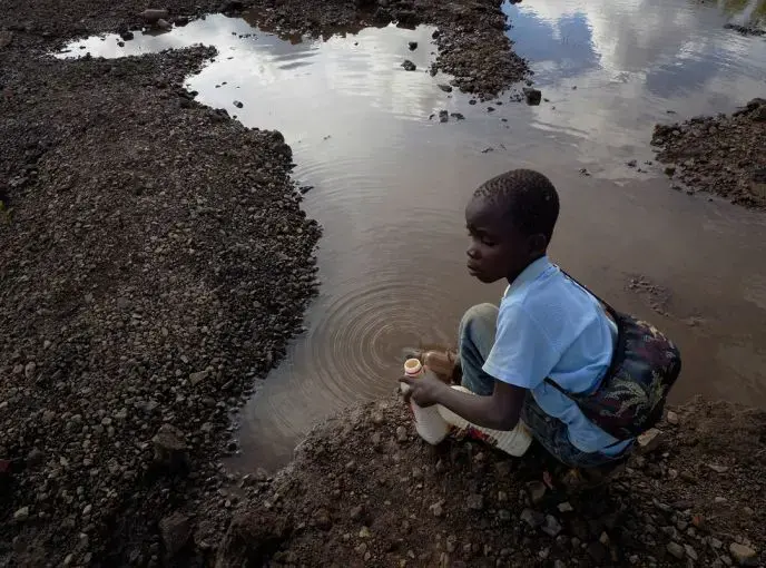 Brian Jovo, 14, collects contaminated water from a pool at Kabwe's Black Mountain. Image by Larry Price. Zambia, 2017.