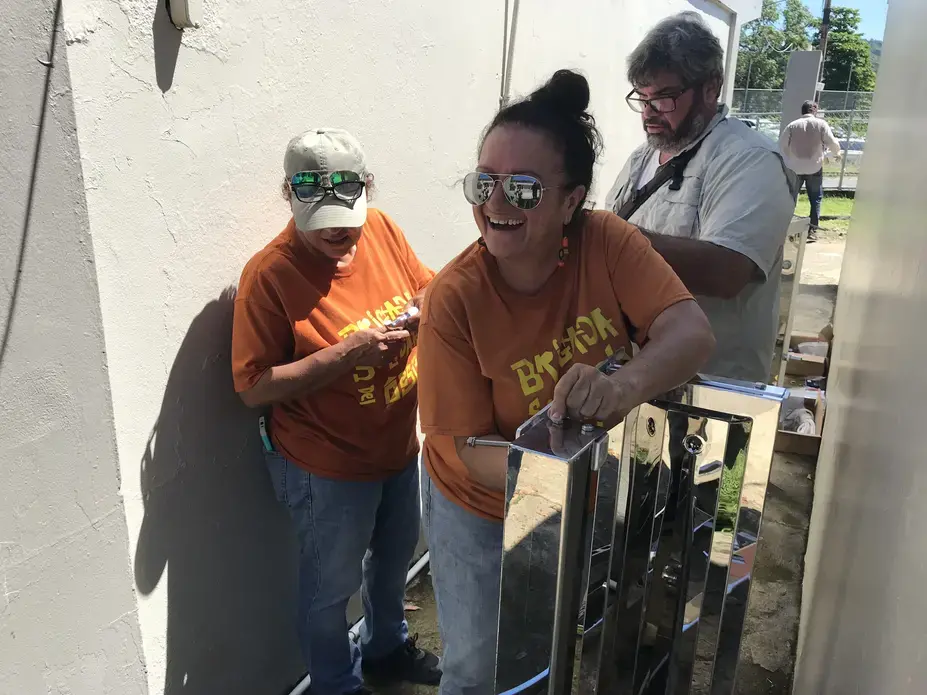 Pagan Gallardo and other volunteers from Brigada Solidaria del Oeste assemble the water tower. Image by Tomas Woodall Posada. United States, 2018.