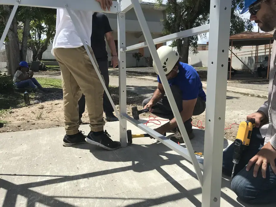 Ludgardo Vendrell of the Rayo De Luna organization secures the water tower to its cement base on the Escuela Espino Elementary School campus. Image by Tomas Woodall Posada. United States, 2018.