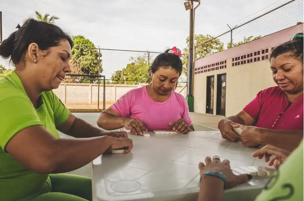 A group of prisoners playing a game of dominos in an outdoor common area in Ana Maria Campos I Prison, Maracaibo. Image by Ana María Arévalo. Venezuela, 2018.