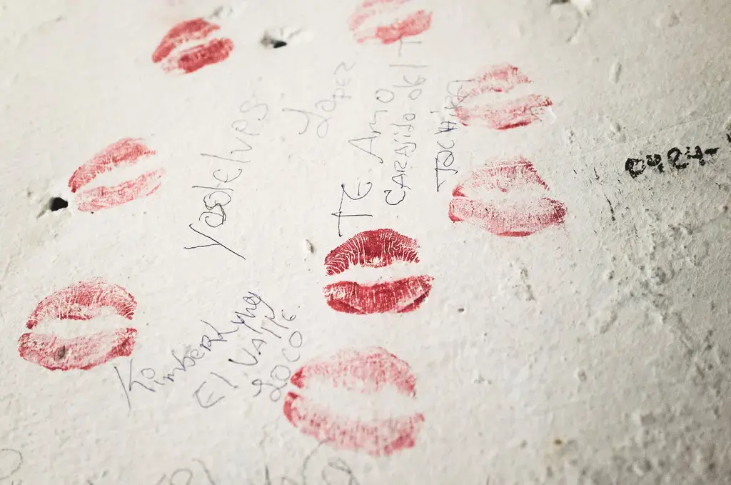 Red lipstick kiss marks and notes on the walls of La Yaguara Detention Center, Caracas, that read “Kymberlyng El Valle Loco” and “Yosolelves Lopez I love you kid.” Image by Ana María Arévalo. Venezuela, 2018.