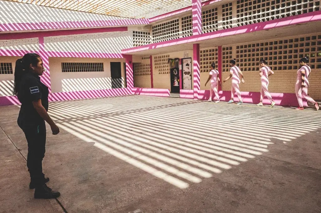 A group of female detainees warm up before exercising under guard inside Ana Maria Campos II Prison, Maracaibo, a “closed” prison — or a center for “feminine formation,” as authorities call it. Image by Ana María Arévalo. Venezuela, 2018. 