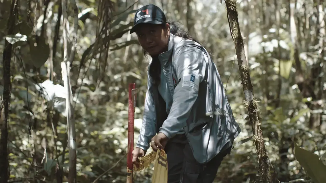 Siona leader Adiela Mera Paz tapes off an area suspected of landmine contamination as part of her work for The Colombian Campaign Against Landmines in Siona territory in December 2019. A still from the New Yorker film “SIONA: Amazon’s Defender’s Under Threat.” Image by Tom Laffay. Colombia, 2019.