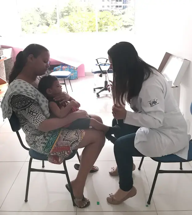 Dr. Isabella Santana, an ophthalmologist at the Altino Ventura Foundation in Recife, Pernambuco, conducts a visual exam with Pedro, a young child born with microcephaly associated with Zika virus, while his mother Juliana holds him. To date, the Altino Ventura Foundation has diagnosed 322 babies with congenital Zika syndrome. Image by Poonam Daryani. Brazil, 2017. Dr. Isabella Santana, an ophthalmologist at the Altino Ventura Foundation in Recife, Pernambuco, conducts a visual exam with Pedro, a young child born with microcephaly associated with Zika virus, while his mother Juliana holds him. To date, the Altino Ventura Foundation has diagnosed 322 babies with congenital Zika syndrome. Image by Poonam Daryani. Brazil, 2017.