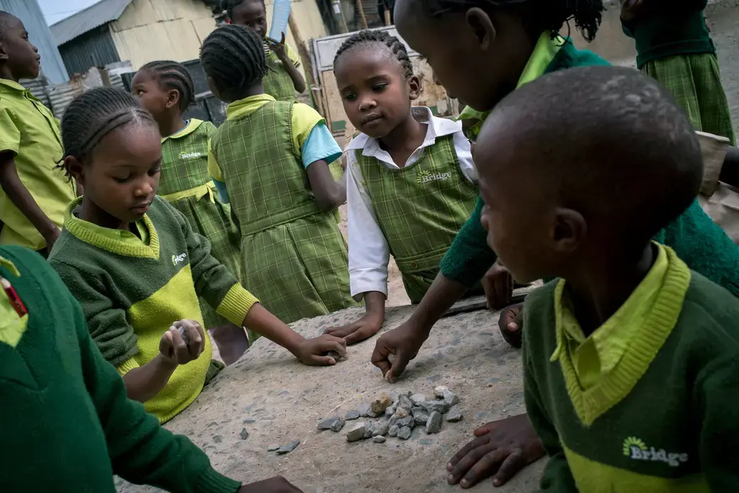 Students play with rocks outside Bridge Diamond in the Mukuru slum in Nairobi. Image by Diana Zeyneb Alhindawi for The New York Times. Kenya, 2017.