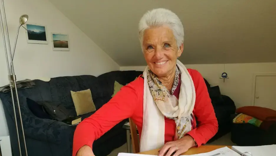 Christa Schmidt is pictured at the table in her apartment in Traunreut, where she tutors refugees in German. Schmidt’s parents were German refugees from Romania. Image by Frank Hessenland. Germany, 2017.