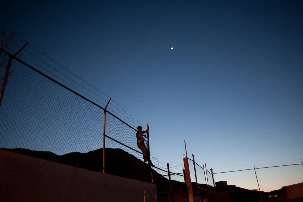 A member of the Novenos climbs a fence. The city closed of the football courts where they hang out in an effort to keep the neighborhood safe. They gather there anyway and worry that if attacked they would be unable to flee. Image by Dominic Bracco II. Mexico, 2016.