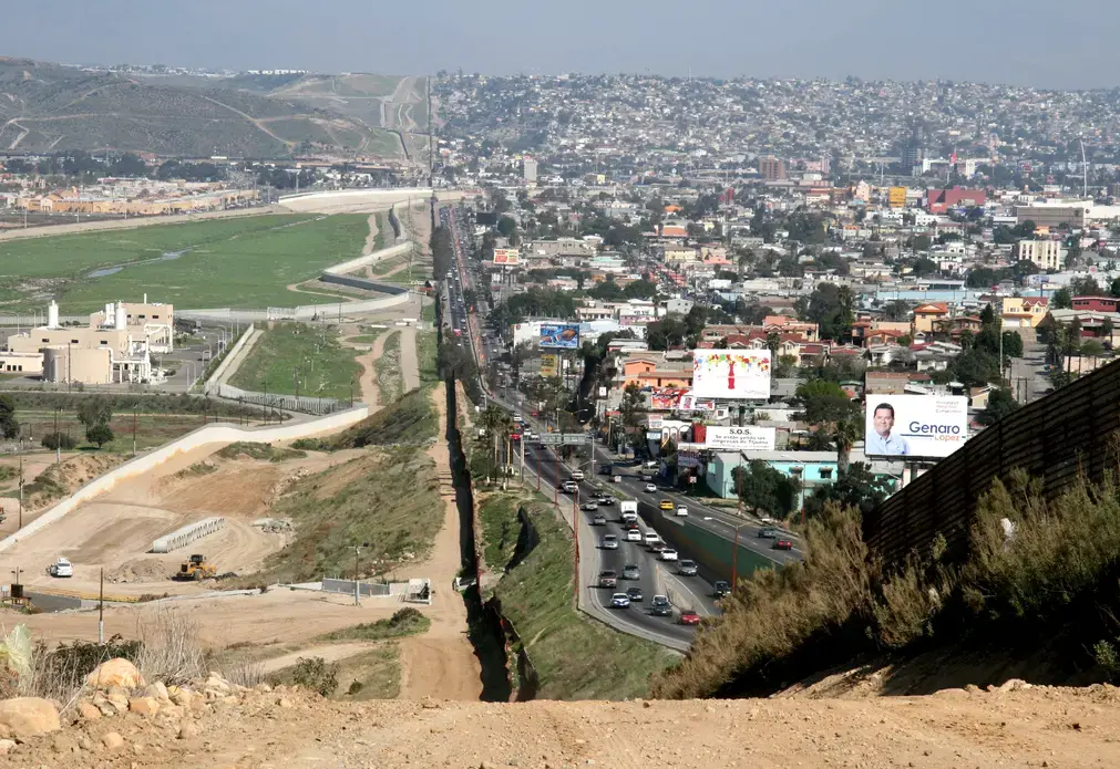 A small fence separates densely-populated Tijuana, Mexico, right, from the United States in the Border Patrol's San Diego Sector. Image by Sgt. 1st Class Gordon Hyde / United States Army. United States, 2007.