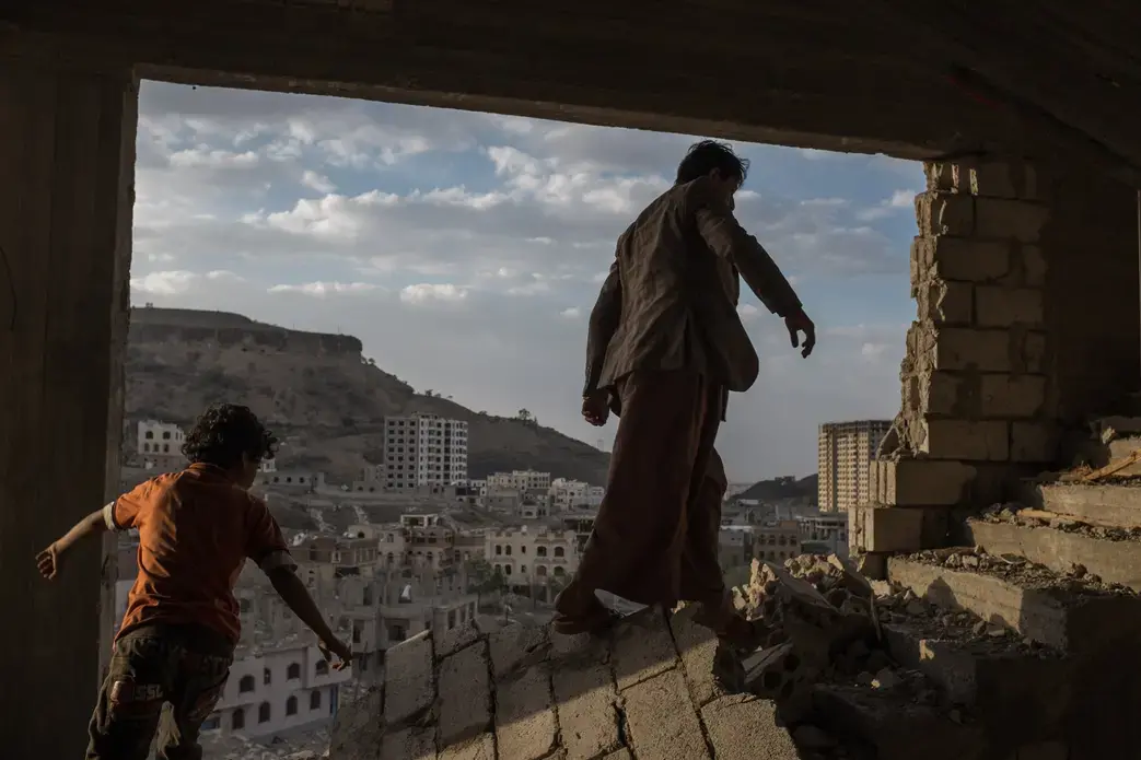 Yemeni brothers climb the broken stairs of an apartment building damaged by airstrikes in the Faj Attan district of Sana, Yemen, in August 2015. Image by Alex Potter. Media file: potter_alex_07.jpg