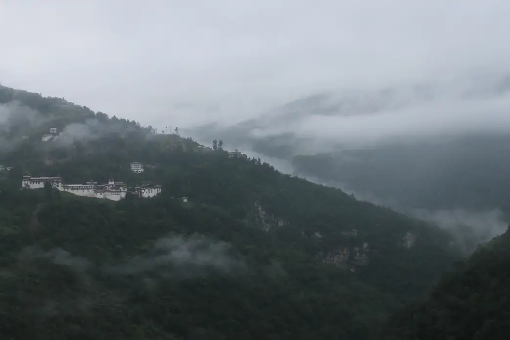 The Trongsa Dzong, or fortress, sits nestled among the trees in the early morning mist in the district of Trongsa. Image by Emma Johnson. Bhutan, 2019.