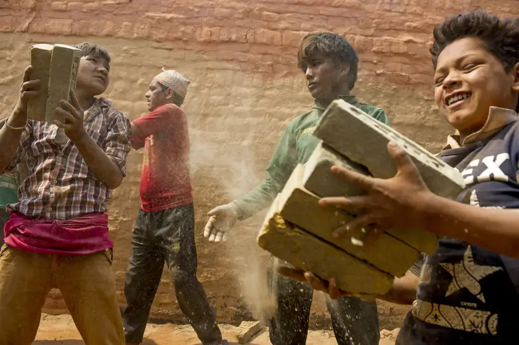 Young boys stack bricks inside the Rakta Kali brick kiln. As many as 60,000 children work in brick kilns across Nepal. Image by Ann Hermes. India, 2016.