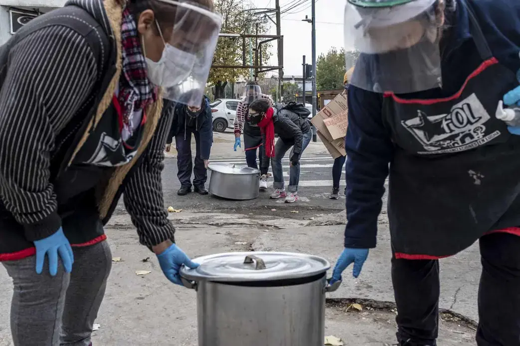 Women from Frente de Organizaciones en Lucha’s “Berta Cáceres” soup kitchen carry their pots for a public soup kitchen in Villa 1-11-14, Buenos Aires, Argentina. Image by Anita Pouchard Serra. Argentina, 2020. Women from Frente de Organizaciones en Lucha’s “Berta Cáceres” soup kitchen carry their pots for a public soup kitchen in Villa 1-11-14, Buenos Aires, Argentina. Image by Anita Pouchard Serra. Argentina, 2020.