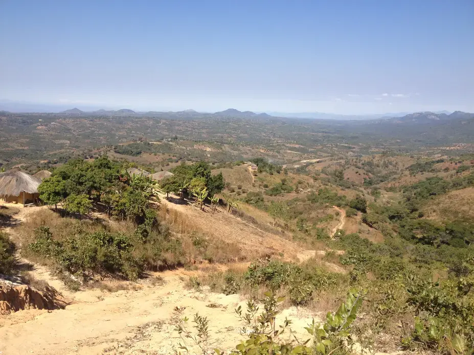 The view on the path from Nsambe to Neno. The government hospital in Neno is not visible, but it sits just in front of the hills in the distance at the center of the photo. With the reintroduction of user fees at Nsambe health center, residents of Nsambe fear they will have to make this journey while sick. Image by Luke Messac. Malawi, 2013. Media file: messac_photo_blog_2.jpg