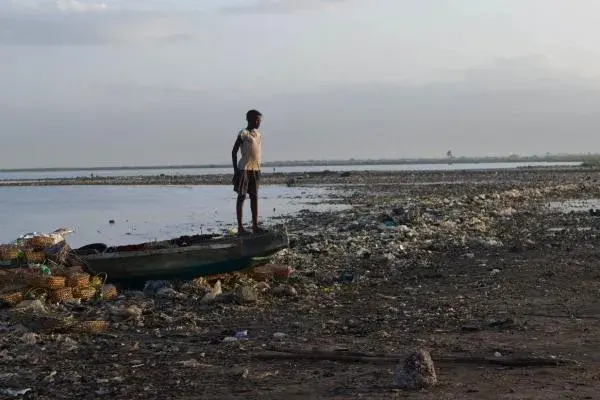 A young girl stands on the bow of a fishing boat docked on the shoreline of Cité Soleil. Image by Meghan Dhaliwal. Haiti, 2012.