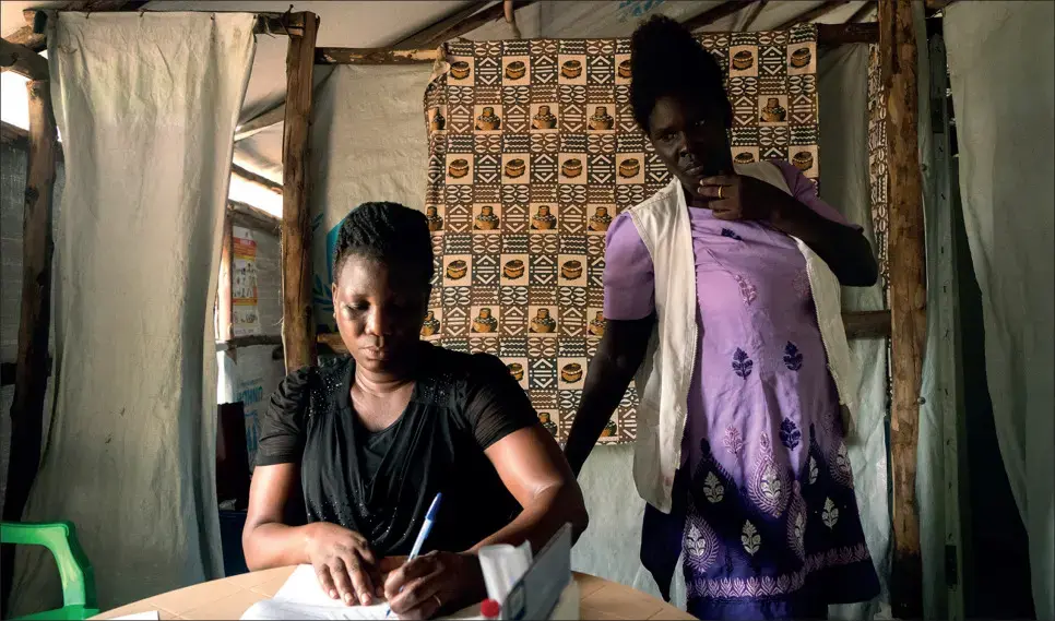 Midwife Susan Oyera, with the help of medical interpreter Grace Ezati, writes a referral for a patient who has a positive HIV test to speak with a psychologist at the Médecins Sans Frontières sexual violence and mental health clinic in the Omugo settlement in the Rhino camp extension in Uganda for refugees from South Sudan.