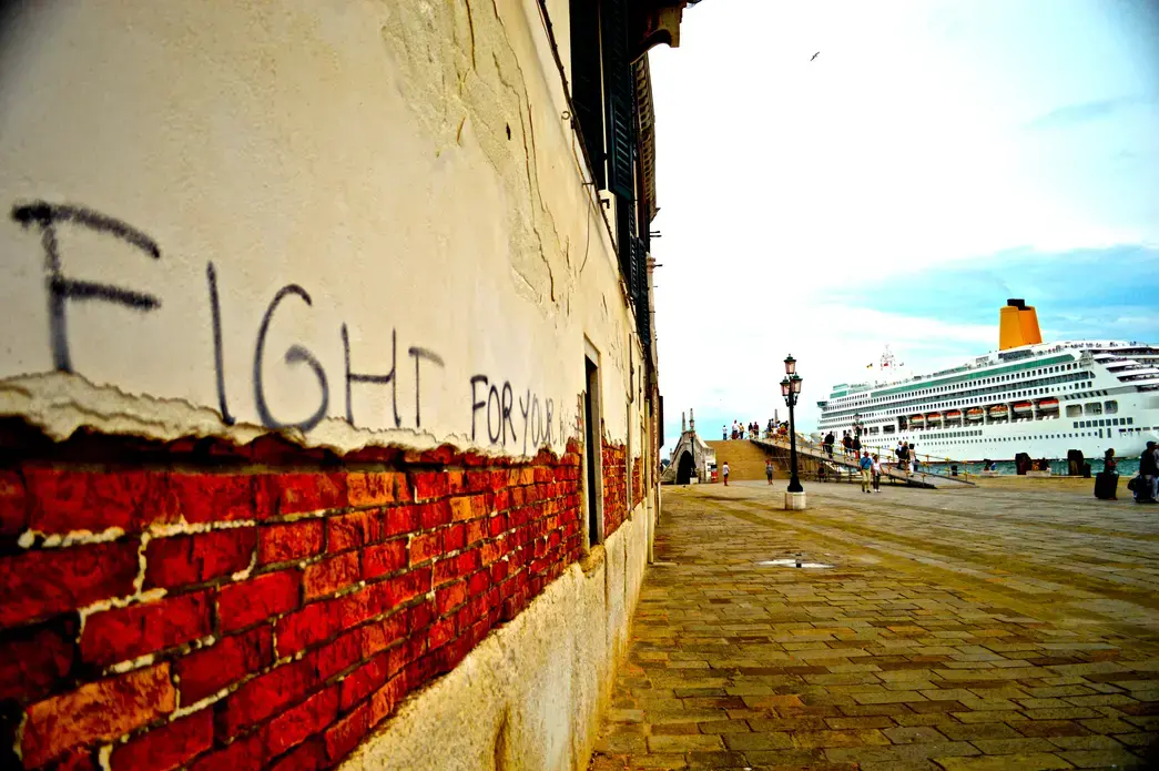 “FIGHT FOR YOUR RIGHT” Graffiti scrawled across a wall in Castello, Venice, screams at the cruise ship lumbering by. Image by Robert Eric Shoemaker. Italy, 2014. Media file: dsc_0047_-_version_2.jpg