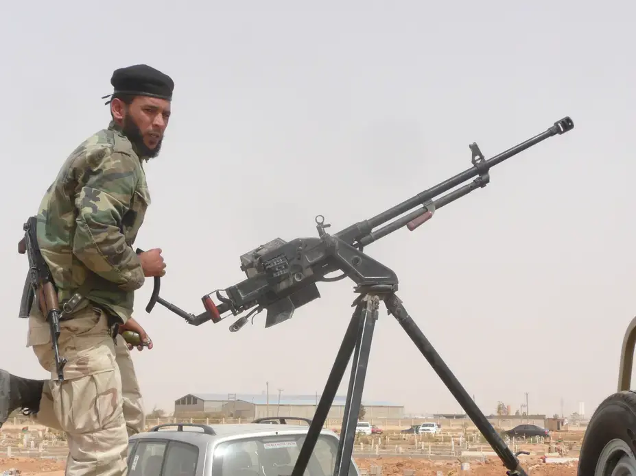 A government soldier primes his gun and grenade at a funeral. Image by Nicolas Pelham. Libya, 2013. Media file: p1160971_-_script_10a_-_a_government_soldiers_primes_his_gun_and_grenade_at_a_funeral.jpg
