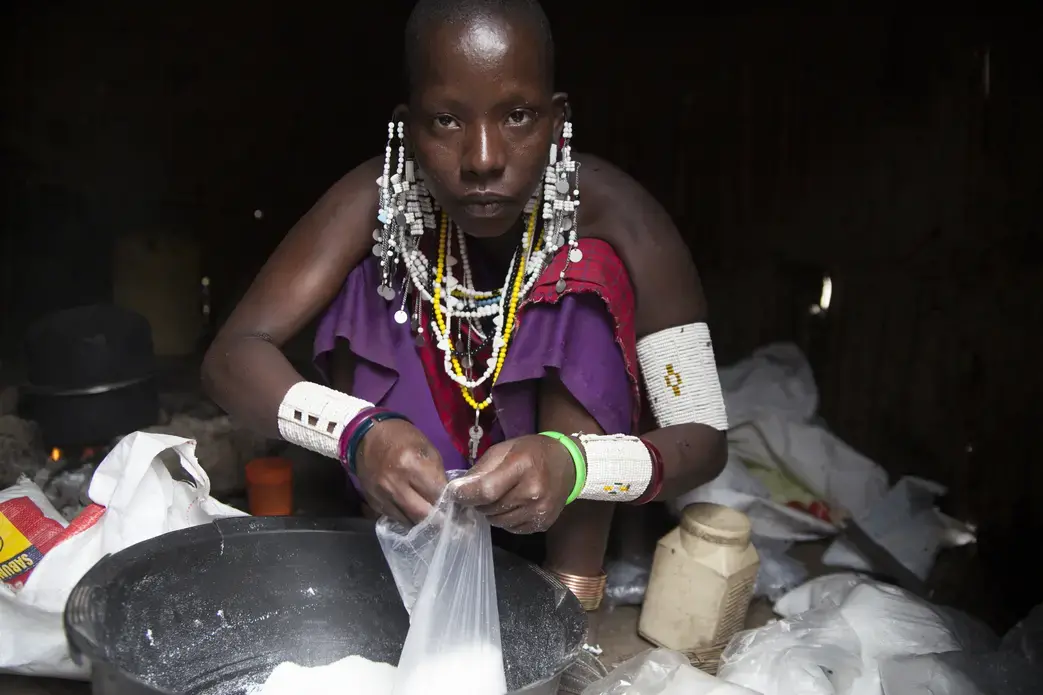 Teresia Kelele, a 27-year-old Maasai mother of two, fills bags of detergent to sell from her house for less than 50-cents each. Using money borrowed from her mother, Kelele sells phone vouchers and detergent in order to provide for her family. A generation of Maasai women in Oltukai Village are starting to sell goods despite sometimes harsh backlash from the community. Image by Sydney Combs. Tanzania, 2015.