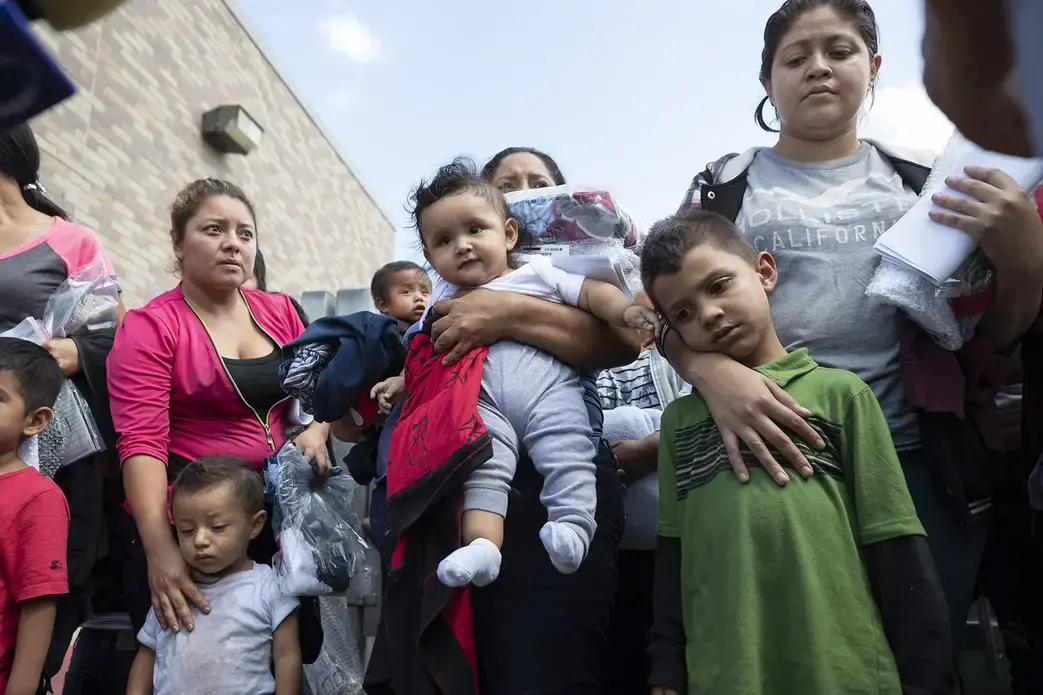 About 25 immigrant mothers and their children caught coming across the Texas-Mexico border are released at the McAllen bus station wearing ankle monitors, on June 22, 2018. Image by Bob Daemmrich. Texas, 2018.