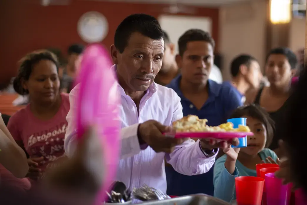 In this July 25, 2019, photo, a Guatemalan man gets a plate of food at El Buen Pastor shelter for migrants in Cuidad Juarez, Mexico. Image by Gregory Bull. Mexico, 2019.