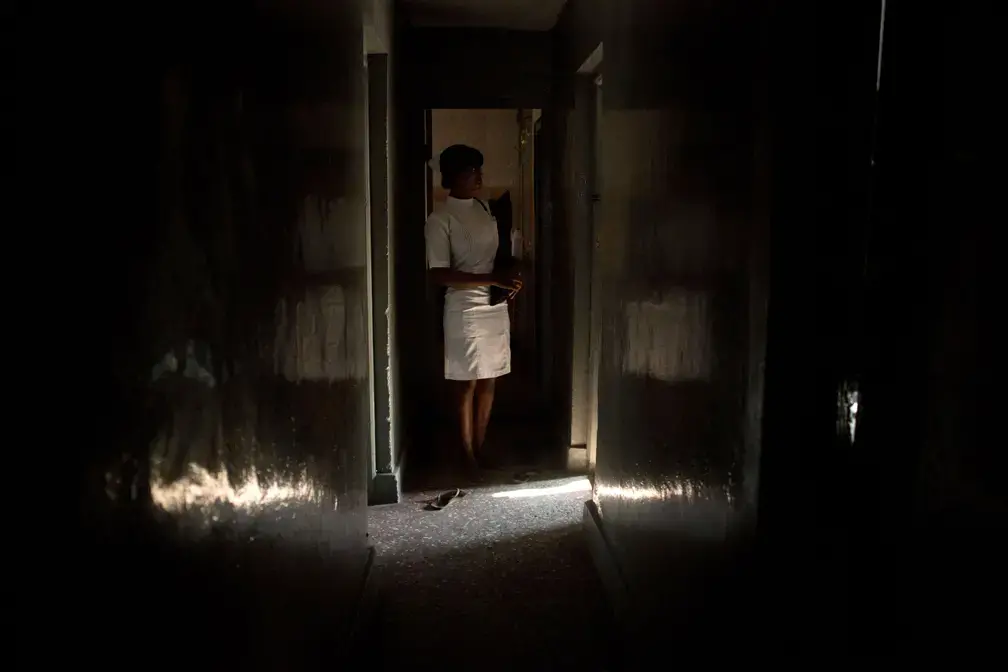 A member of the medical staff of a licensed doctor known for providing abortions stands in doorway of the operating room of his private clinic, located blocks from one of the biggest public hospitals in Lagos; in Lagos, Nigeria, August 22, 2013. They asked that their identities not be disclosed. Image by Allison Shelley. Nigeria, 2013. Media file: nigeria_abortion_projectpage_main.jpg